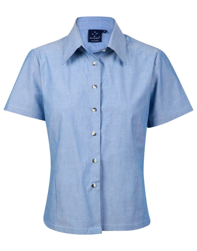 A short-sleeve ladies' button-up shirt in light blue chambray with a collar and shiny buttons.