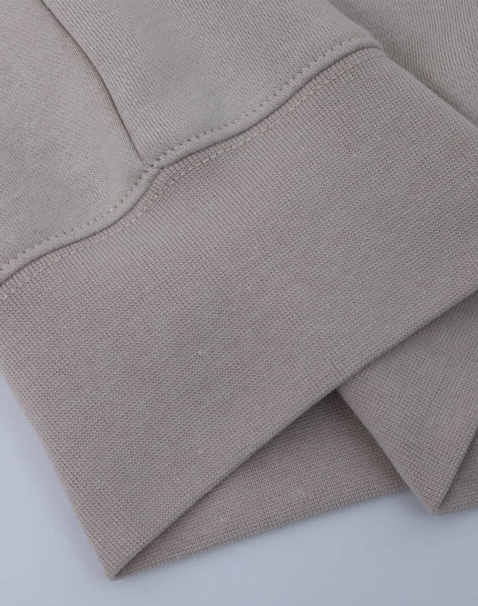 A light beige crew fleece jumper with a smooth texture and cuffed sleeves. It features a logo on the fabric.