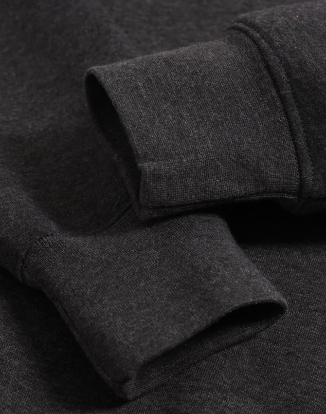 A close-up of the cuffs of a dark grey polar fleece jumper featuring a logo.