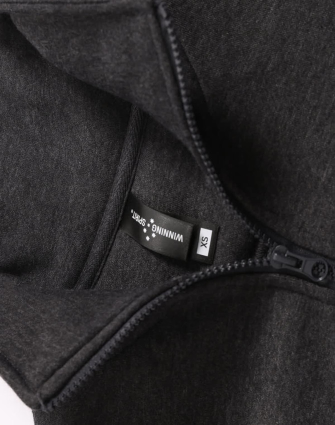 A 1/2 zip collar fleecy jumper in dark grey, featuring a hang tag and a zip closure. It has a logo.