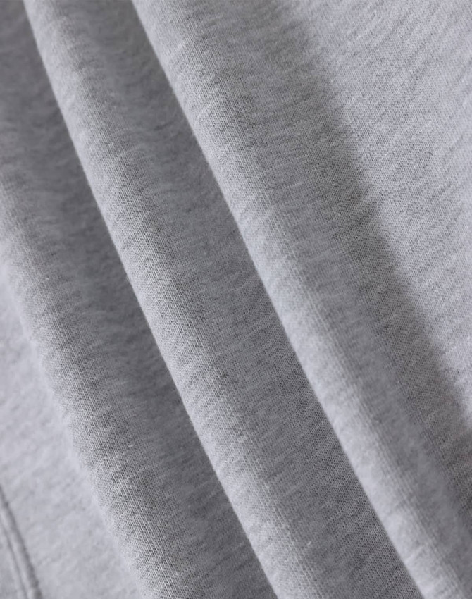 A close-up of soft grey fabric, highlighting multiple folds and textures of a fleecy hoodie.
