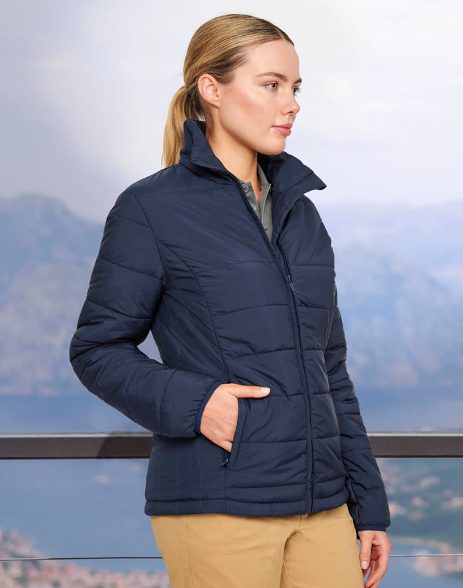 A navy insulated puffer jacket with a 3D cut and side pockets, displayed on a model against a scenic backdrop.
