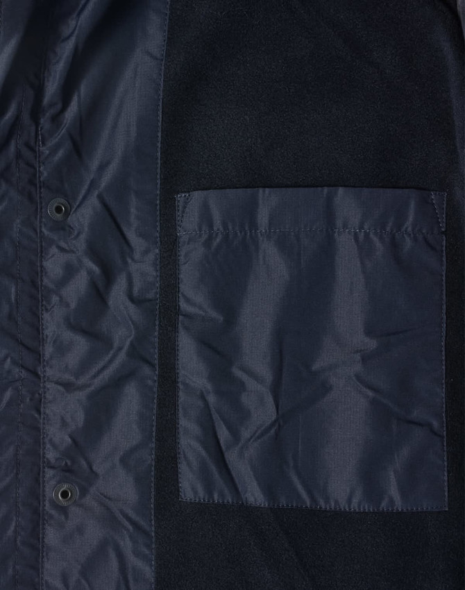 A dark navy unisex jacket featuring a large chest pocket and snap button closures. Includes a logo on the fabric.