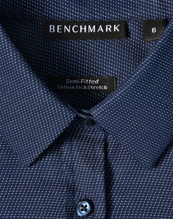 Ladies' pin dot stretch long sleeve shirt in navy with a button closure, featuring a logo label inside the collar.