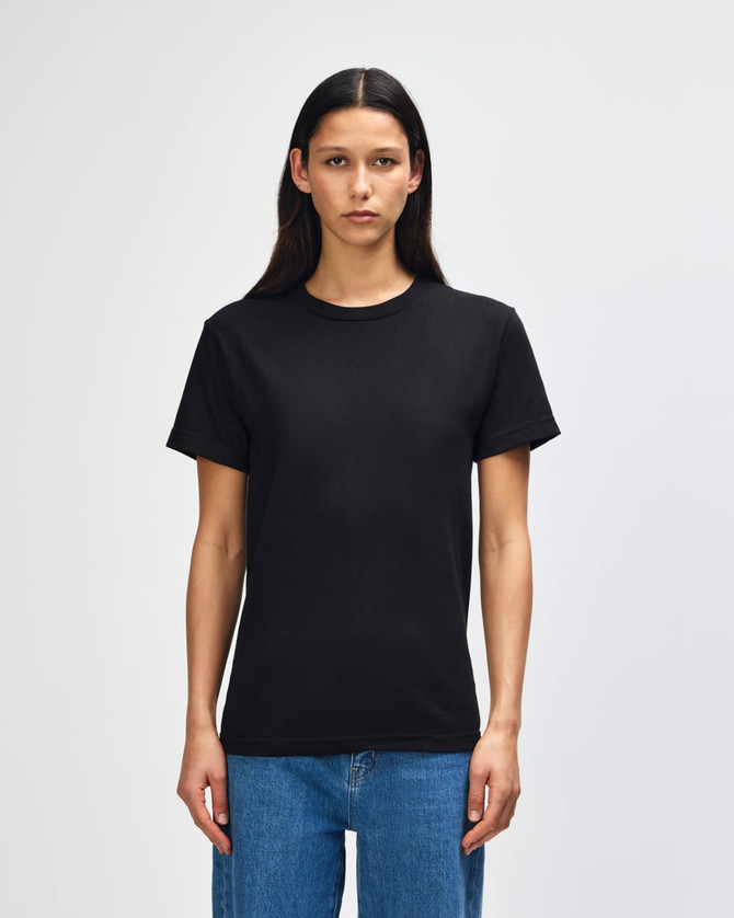A heavyweight cotton unisex T-shirt in black displayed on a model, featuring a simple design and short sleeves.