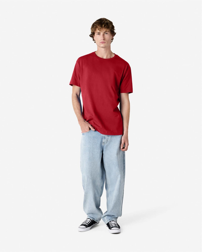 A model wearing a red heavyweight cotton unisex T-shirt paired with light blue jeans and black sneakers.