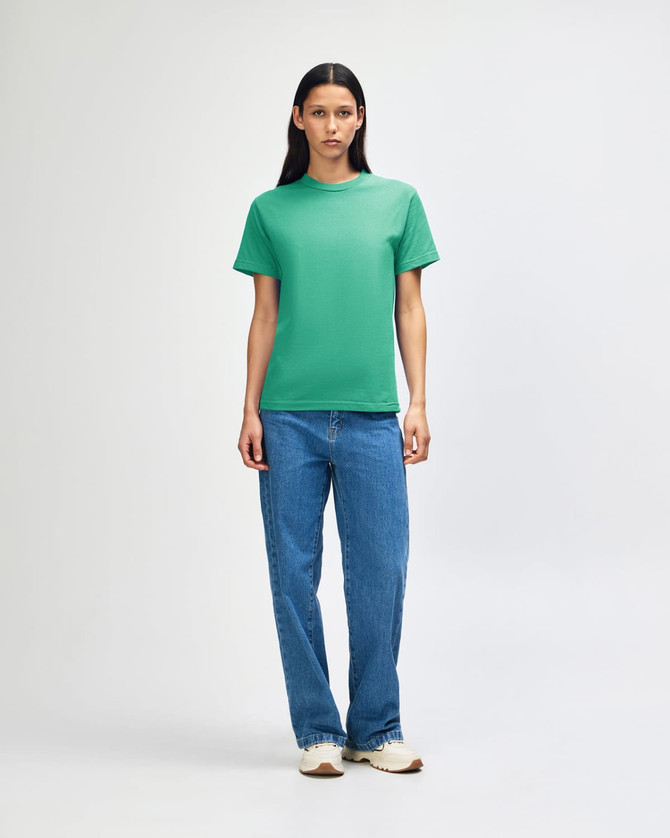 A green heavyweight cotton unisex T-shirt displayed on a model, paired with light blue cargo pants.