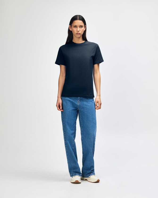A heavyweight cotton unisex t-shirt in navy blue, displayed on a model wearing blue denim jeans.