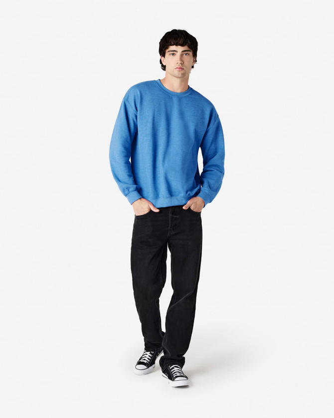 A blue Gildan Heavy Blend adult crewneck sweatshirt paired with black jeans and sneakers, featuring a logo.