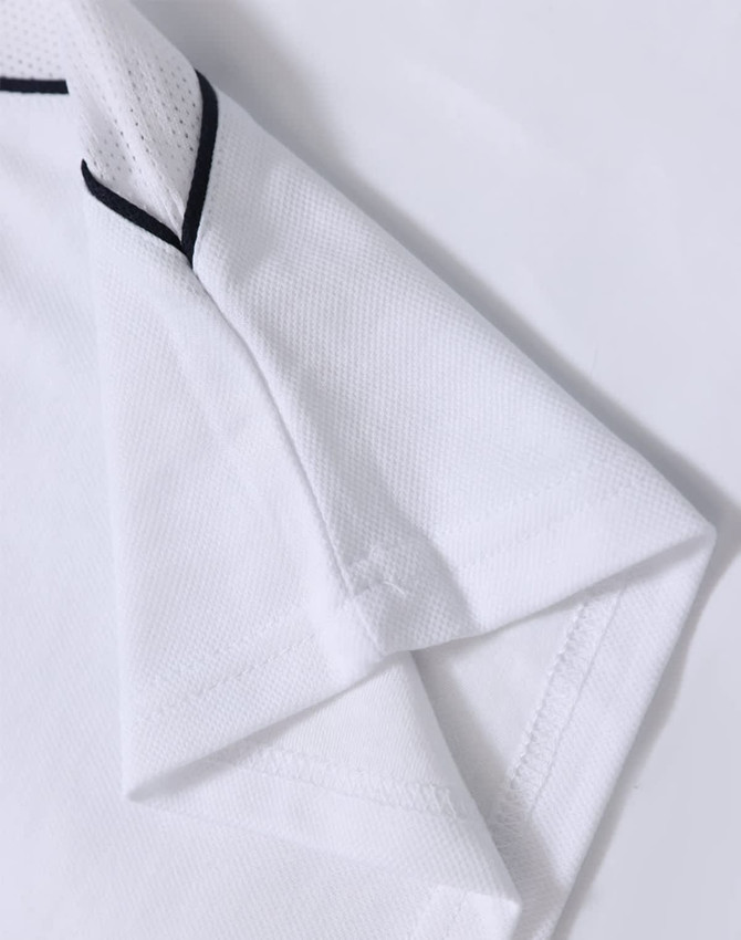 A white kids’ polo shirt with short sleeves and black detailing, featuring a logo.