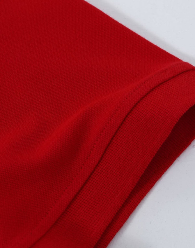 A close-up view of a red men's cotton stretch polo shirt featuring a folded sleeve. It has branding on the fabric.