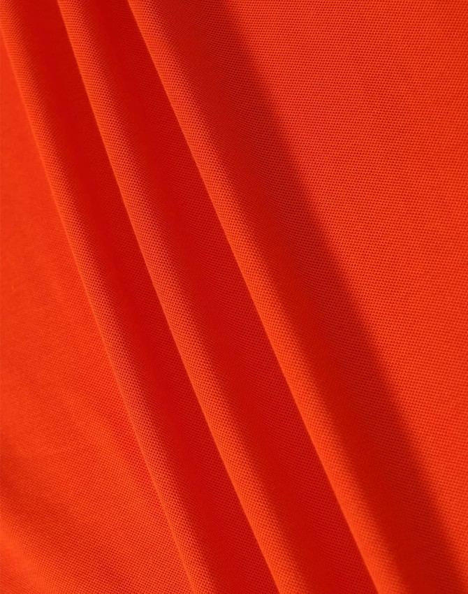 A close-up of orange fabric featuring a textured surface, ideal for polo shirts. The image includes a logo.