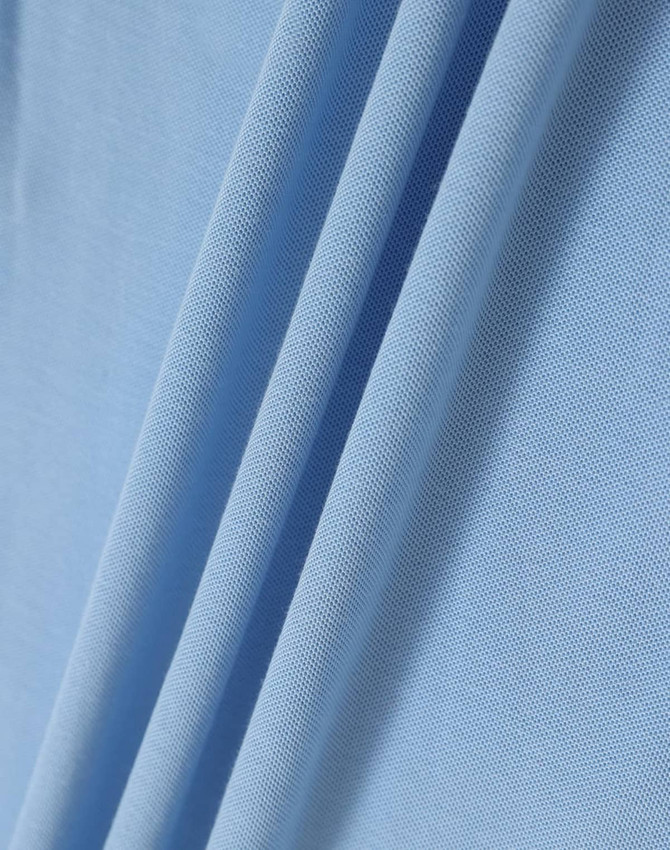 A close-up of light blue fabric, showcasing the texture and folds of a polo shirt material.