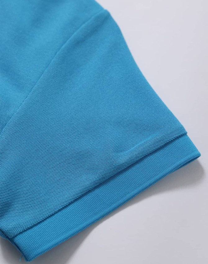 A close-up of a turquoise polo shirt sleeve, featuring a textured fabric and a logo.