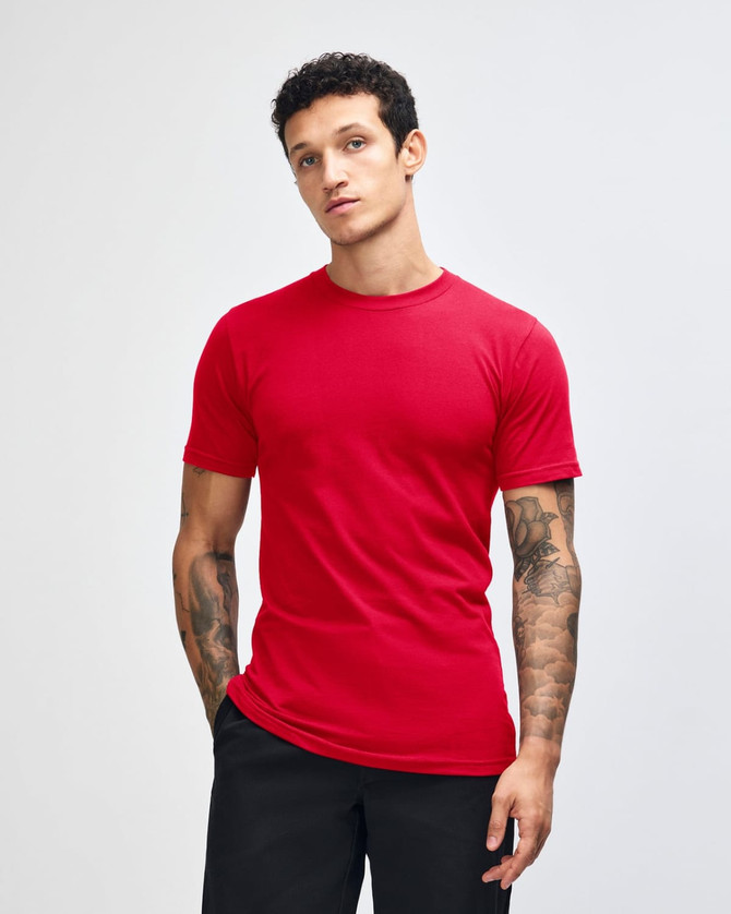 A red unisex fine jersey short sleeve t-shirt displayed on a model with curly hair. It features a logo.