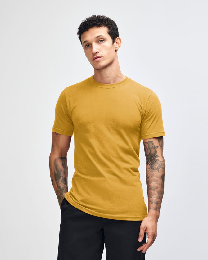 A unisex fine jersey short sleeve t-shirt in mustard yellow, displayed on a model with long hair.