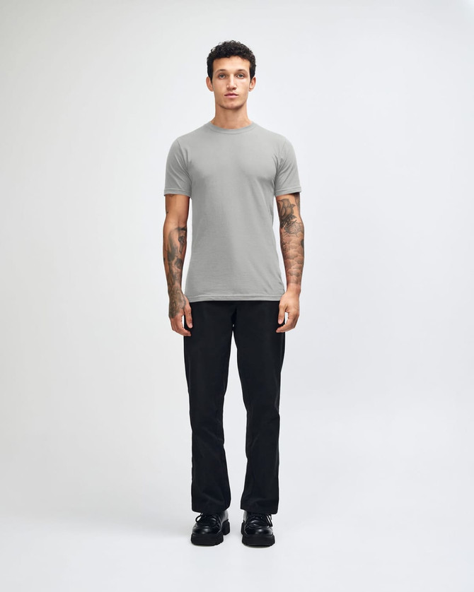 A grey unisex short sleeve t-shirt displayed on a model wearing loose-fitting denim jeans and sneakers.