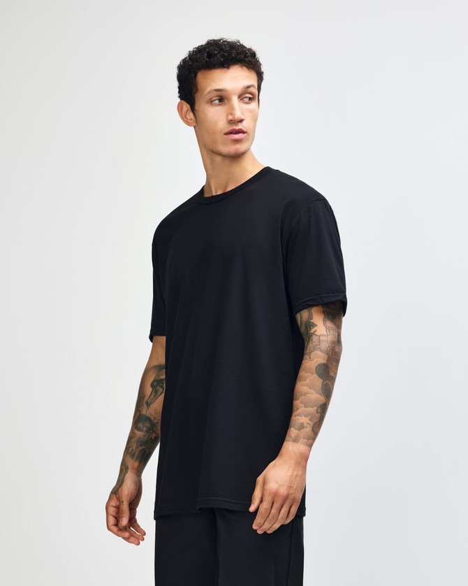 A black unisex short sleeve t-shirt displayed on a model with curly hair, set against a plain background.