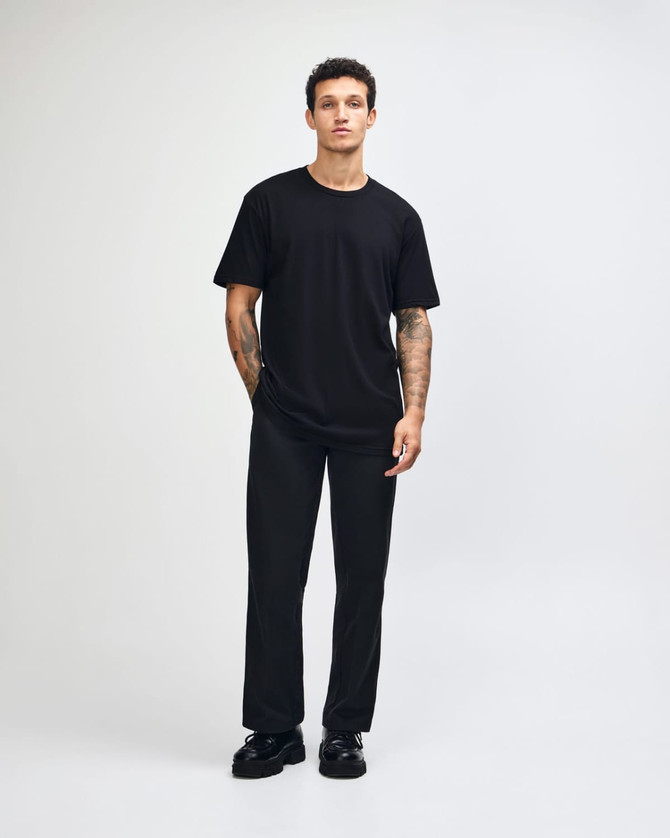 A black unisex fine jersey short sleeve t-shirt displayed on a model, featuring a simple design and relaxed fit.