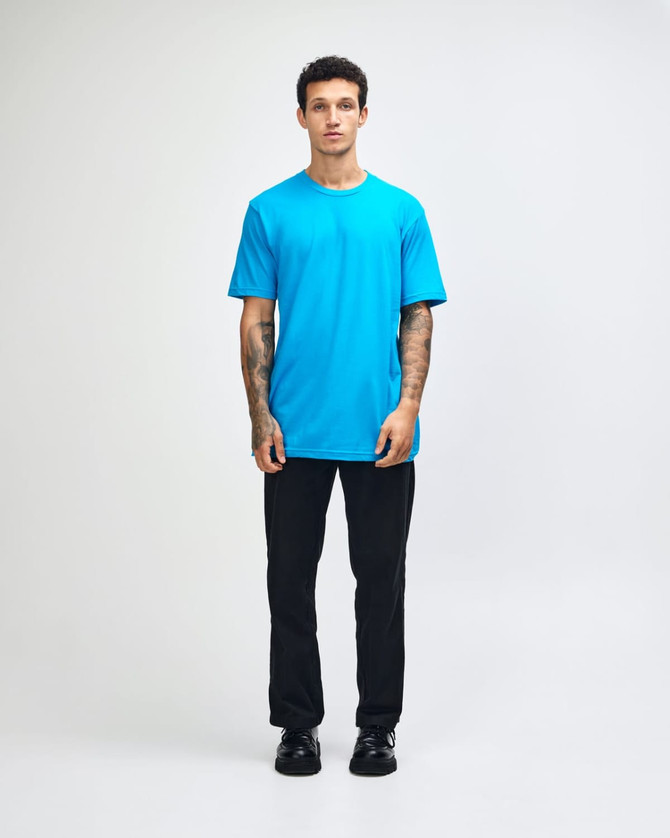A man wears a bright turquoise unisex fine jersey short sleeve T-shirt, with a logo on the shirt.