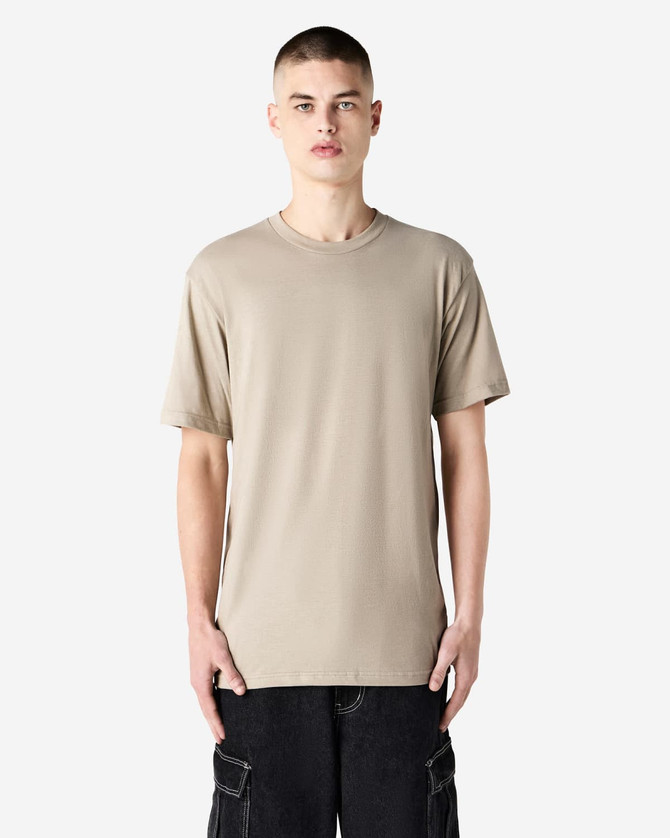 A unisex short sleeve T-shirt in a neutral beige colour, displayed on a model. It features a simple design and logo.