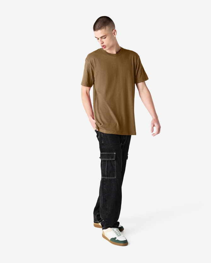A model wearing a unisex short sleeve T-shirt in olive green, paired with black cargo pants and sneakers.