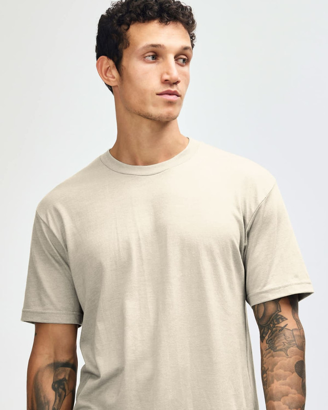 A unisex CVC short sleeve t-shirt in a light beige colour, featuring a simple design and a logo.
