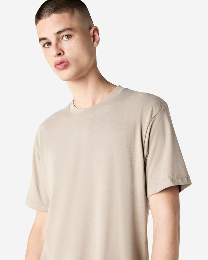 A unisex CVC short sleeve t-shirt in a light beige colour, featuring a simple design and a logo.