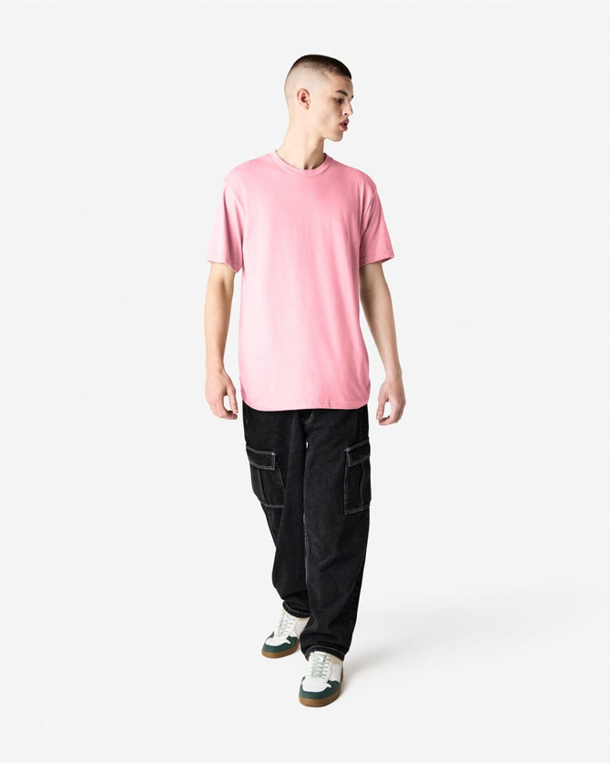 A model wearing a pink unisex CVC short sleeve t-shirt paired with dark cargo pants and trainers.