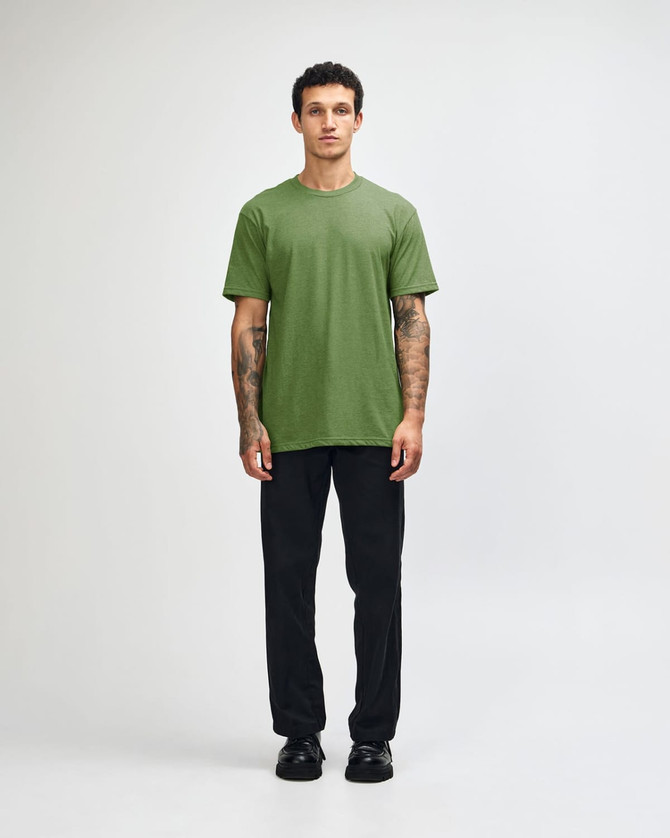 A model wearing a green unisex CVC short sleeve T-shirt paired with black cargo pants and sneakers.