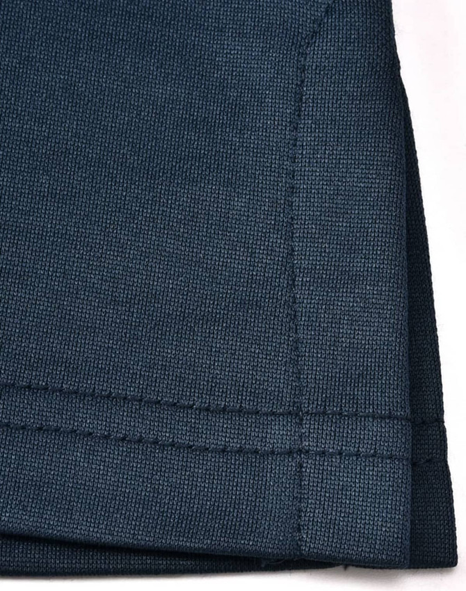 A close-up of a dark navy polo shirt, featuring a textured fabric and a neatly stitched hem. The shirt has a logo.