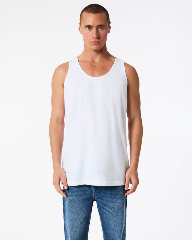 A white unisex fine jersey tank top displayed on a model, paired with blue jeans. The tank features a logo.