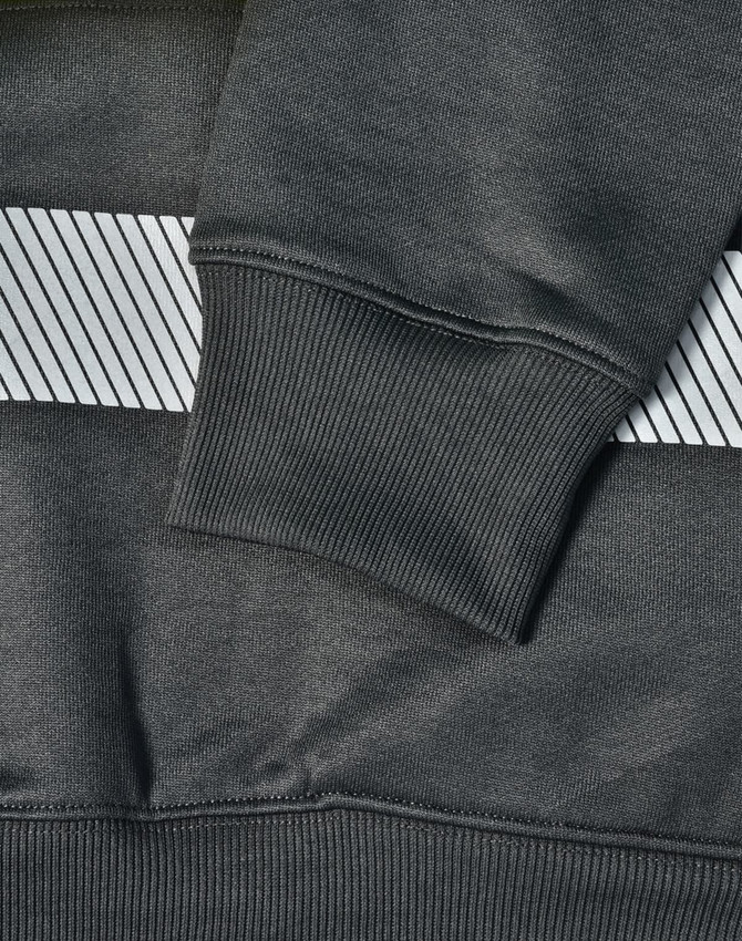 A close-up of a dark green jumper featuring a grey striped pattern and ribbed cuffs, with a branding logo.