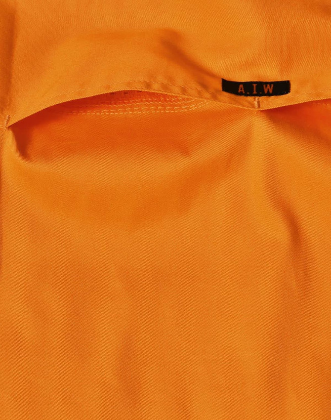 An orange work shirt featuring a pocket and a tag with a logo.