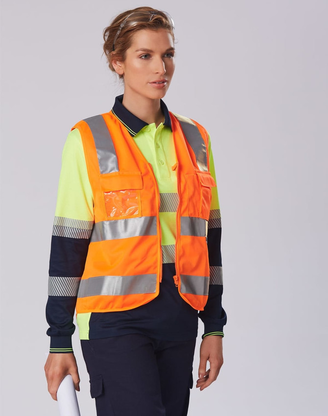 A safety polo shirt in bright yellow and navy with reflective stripes and a logo. A person is wearing it with a safety vest.