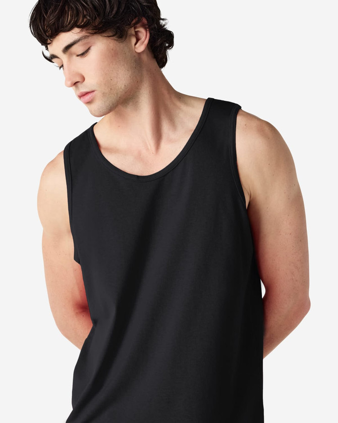A black Gildan Heavy Cotton adult tank top displayed on a model. The tank features a round neckline and a relaxed fit.