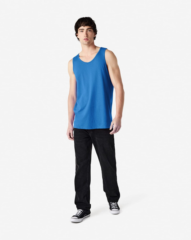 A blue tank top displayed on a model wearing black pants and sneakers, featuring a logo.