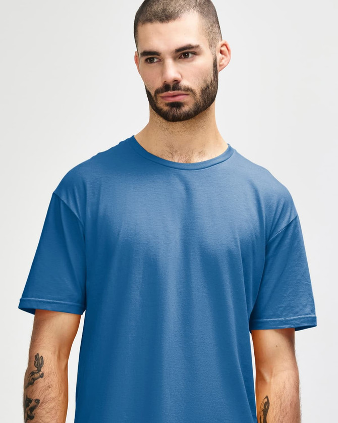 A man wears a Gildan Softstyle adult t-shirt in a deep blue colour, featuring a round neckline and short sleeves.