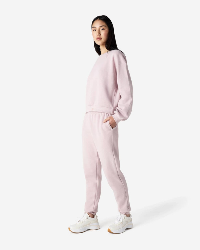 A pair of pink unisex sweatpants made from fleece, featuring a logo and side pockets.