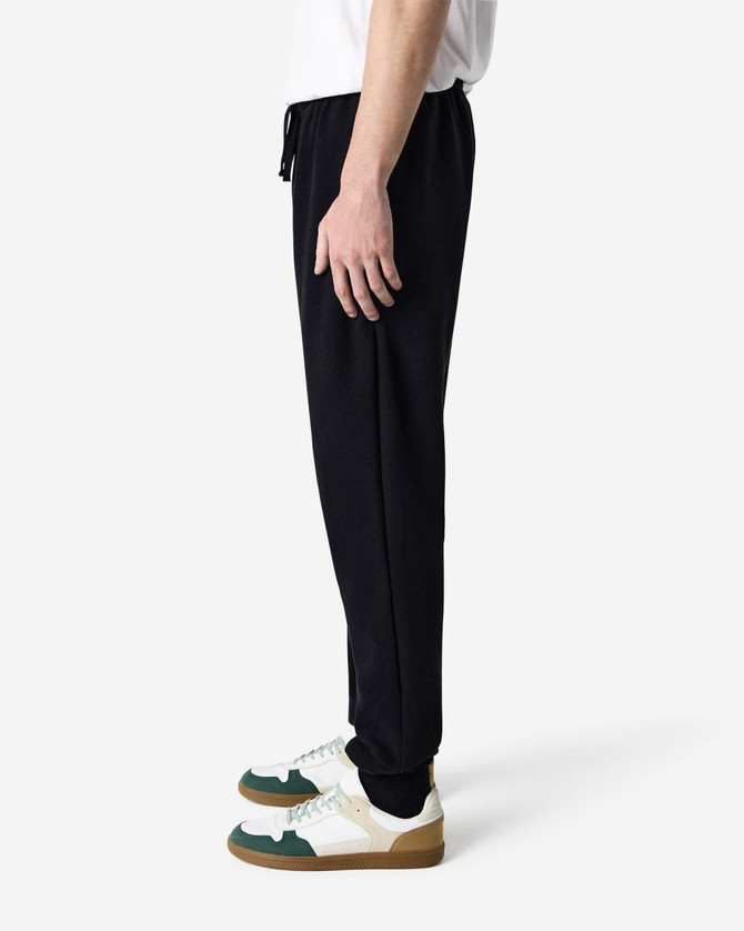 Unisex sweatpants in black with a drawstring waist, showcased on a model standing sideways.