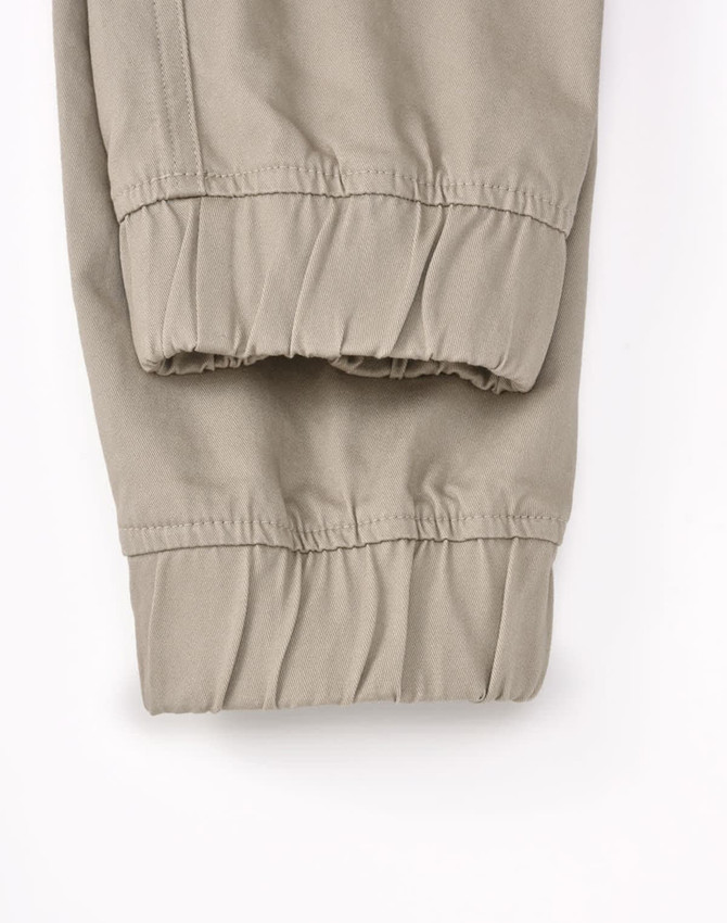 A pair of unisex cotton stretch drill cuffed work pants in khaki, featuring elastic cuffs and a simple design.