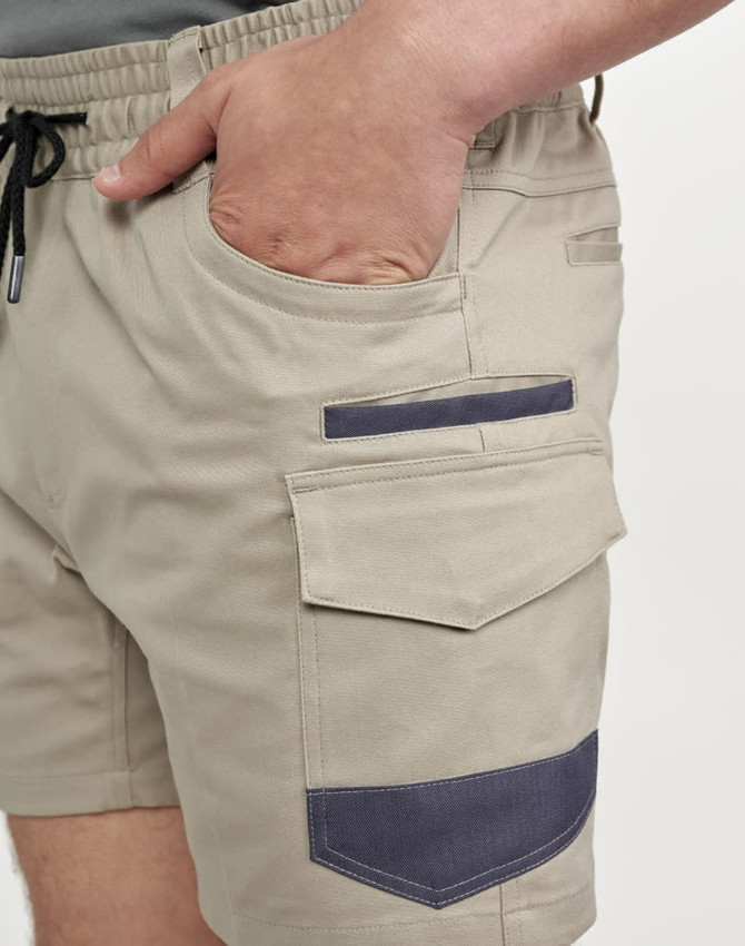 Work shorts in beige with dark navy accents, featuring pockets and an elastic waistband. The shorts have a logo.