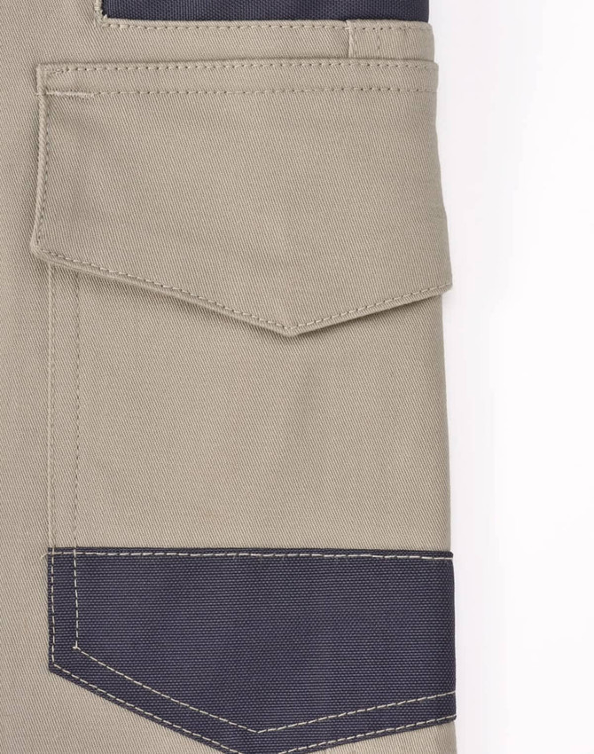 A close-up of unisex cotton stretch drill work shorts in khaki with navy blue detailing and pockets. Includes a logo.