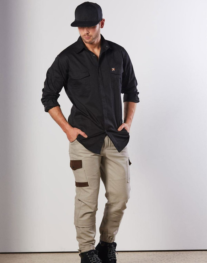 A model wearing a black long-sleeve work shirt and beige cargo pants, featuring two chest pockets and a logo.