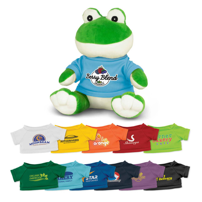 A green and white frog plush toy wearing a blue T-shirt, surrounded by various coloured T-shirts.