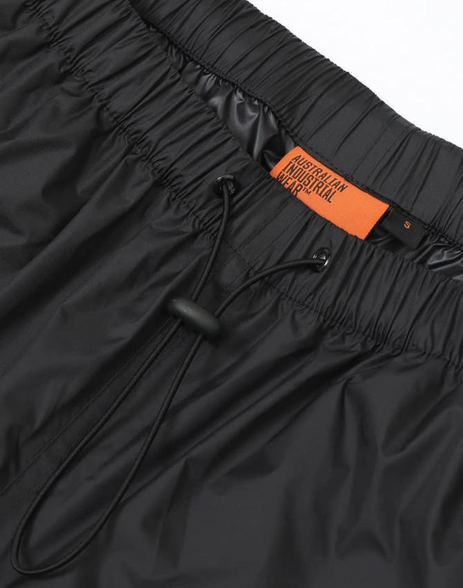 Lightweight black nylon waterproof rain pants with an elasticated waistband and drawstring, featuring a logo label.