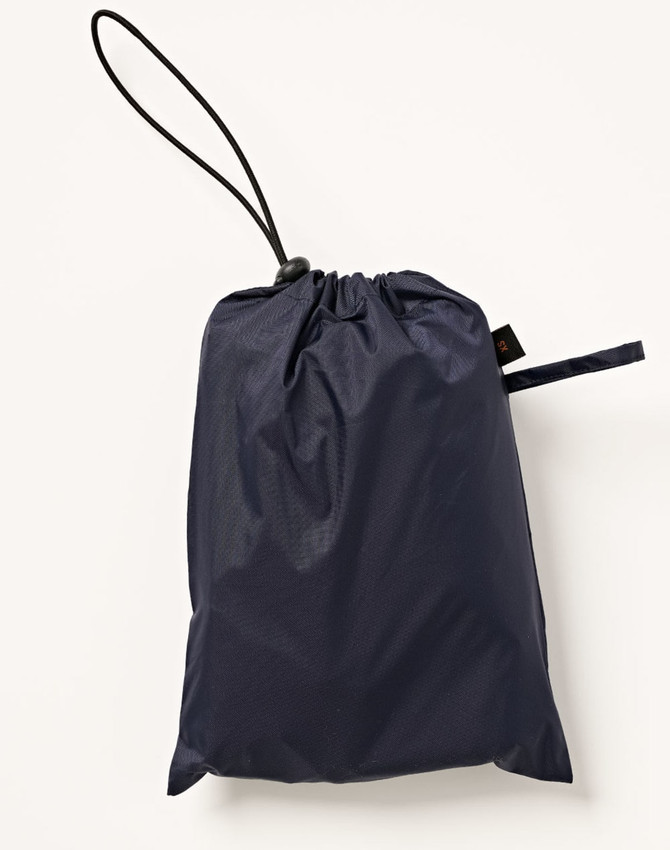 A navy blue waterproof rain pants packed in a drawstring bag with a toggle. Features a logo on the bag.