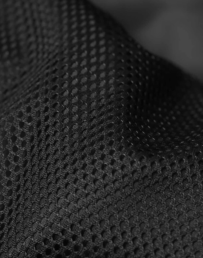 A close-up of black mesh fabric with a textured pattern, showcasing its breathable design and material quality.