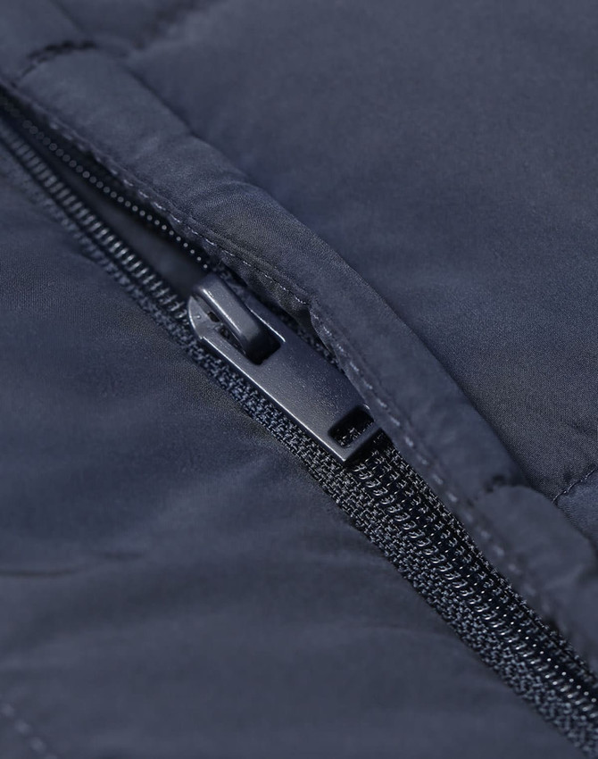 Close-up of a navy insulated puffer vest featuring a zippered pocket and a subtle logo.
