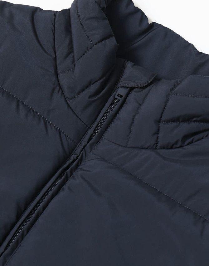 A dark navy insulated puffer vest with a high collar and zipper, featuring a fabric texture and stitching details.